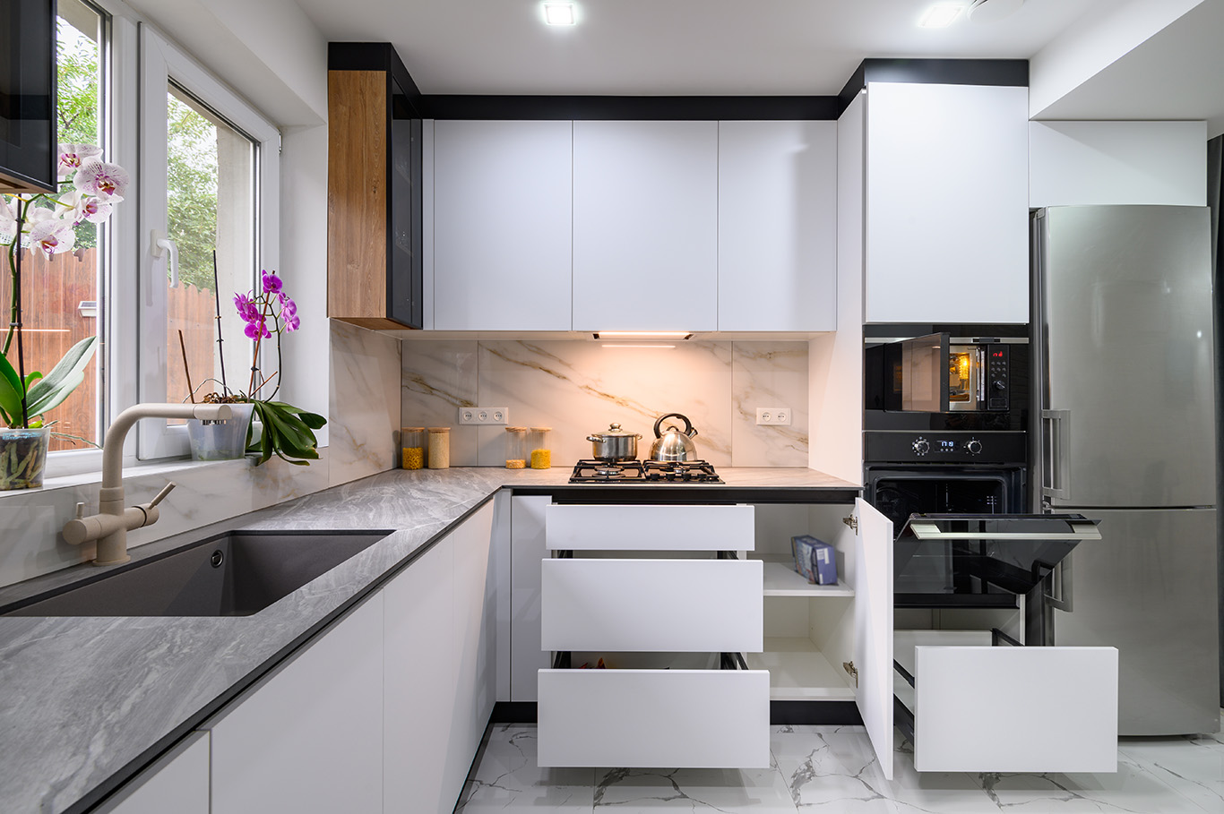 A bright and airy kitchen with a white, modern design, a luxurious marble floor, an open oven door, and pull-out shelves for easy access to ingredients and appliances